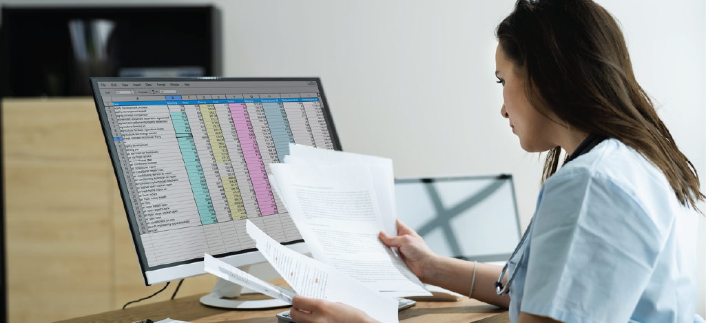 Female medical staff checking patient invoices using a computer.
