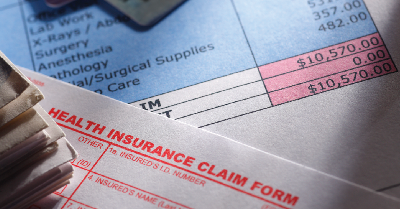 Achieving clean claims - Medical insurance claim form on a table with a medical bill and credit cards.