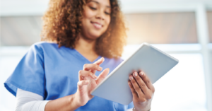 Female medical professional holding a digital tablet device while using the hospital’s EMR system.
