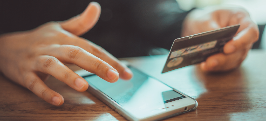 A person holding a credit card and using a smartphone to pay for medical bills.