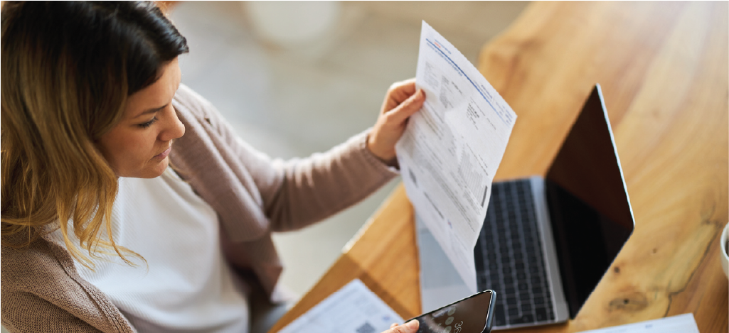 Creating a patient-centric billing approach - Woman at home computing medical bills using her smartphone’s calculator.