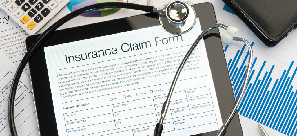 Insurance claim form on a tablet device together with a stethoscope and other documents.