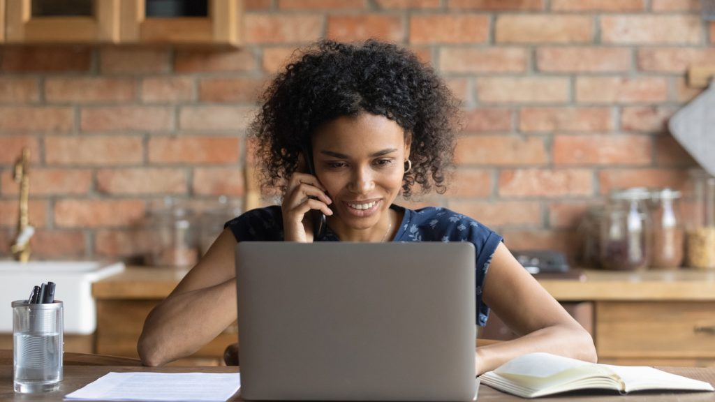 A woman is using her laptop to pay medical bills and calling her healthcare provider about text and email medical billing options