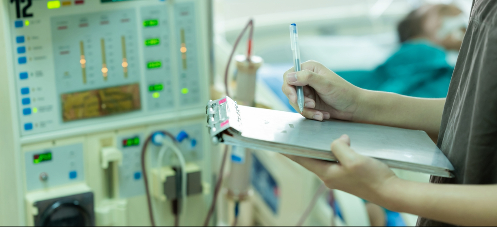 Dialysis Billing Challenges: Nurse checking a dialysis machine while a patient receives treatment at a dialysis center.