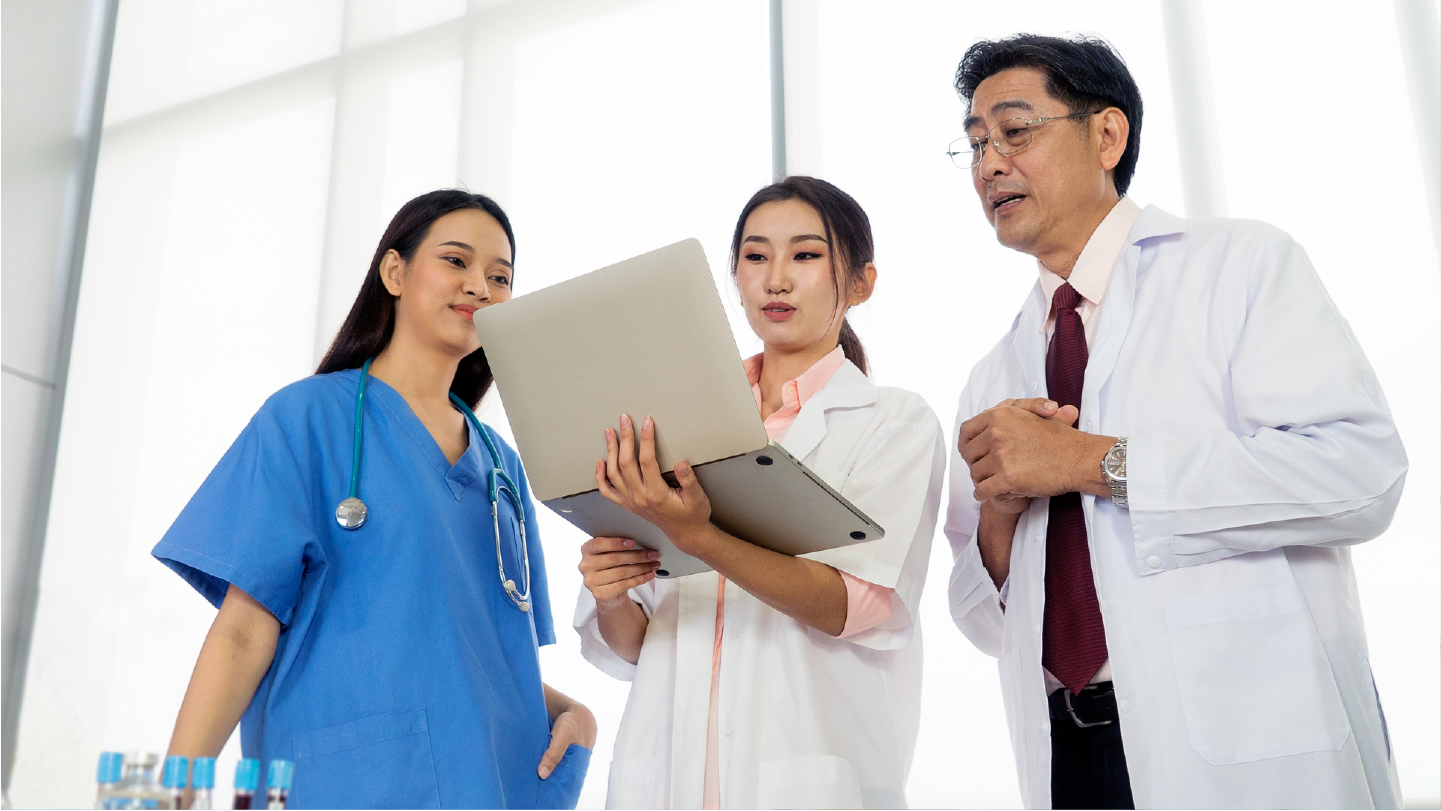 A group of doctors looking at a computer talking about their healthcare revenue cycle