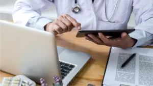 A doctor reviewing their revenue cycle management on a tablet and computer