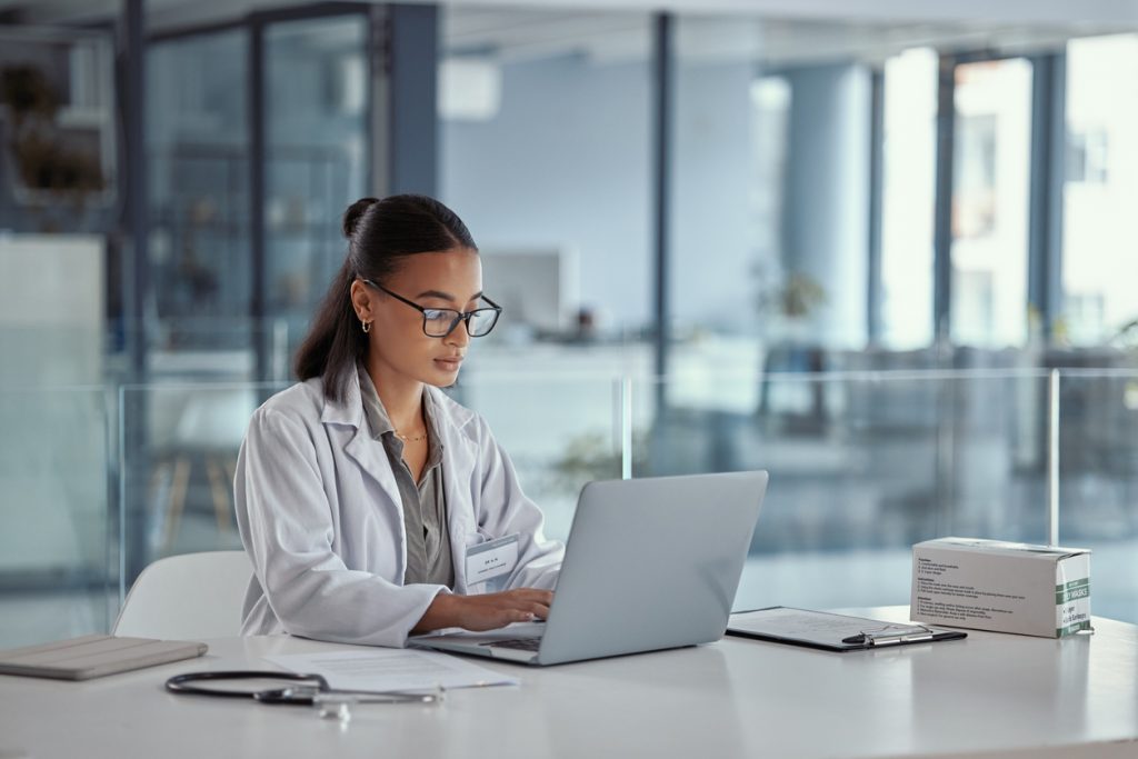  A female doctor using a computer to access her medical practice’s revenue cycle management system.