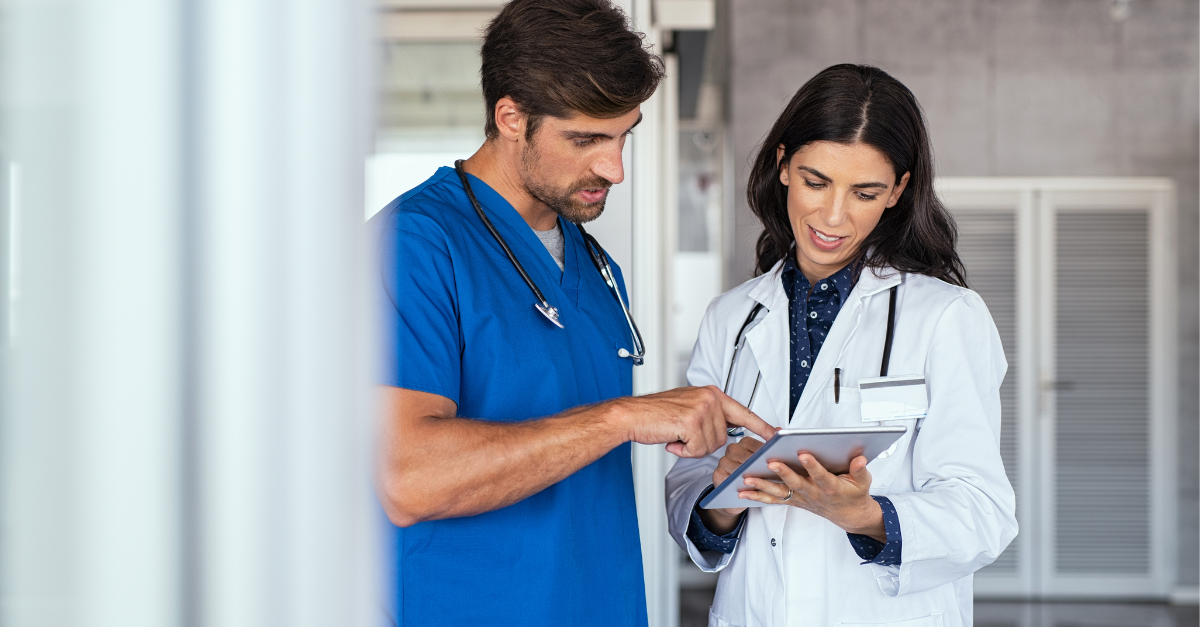 Two doctors talking about increasing faster payments from patients while looking at a tablet