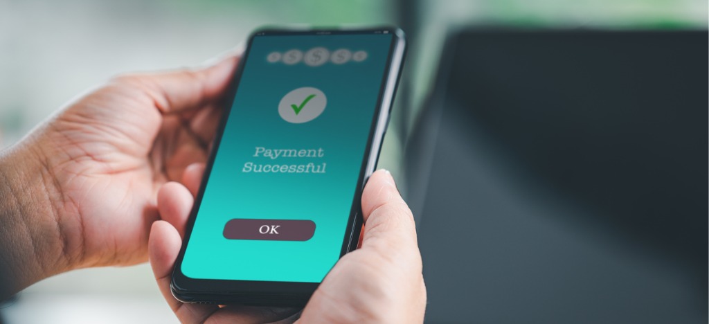 Leveraging the benefits of eBills - A man holding his smartphone showing successful bill payment.