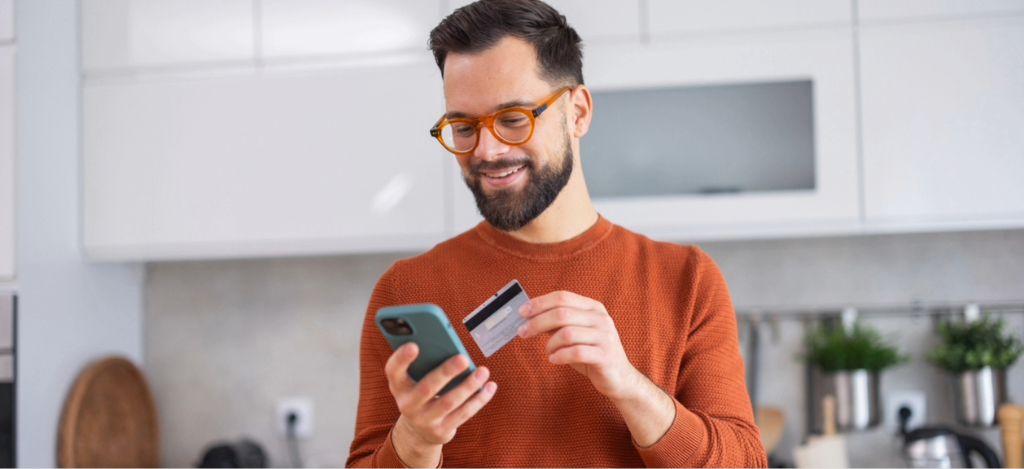 Revenue cycle management companies - A man at home paying his medical bill online through his smartphone.