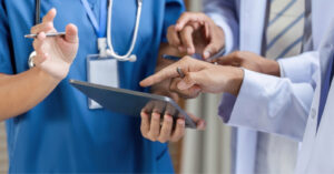 Medical billing issues - A group of doctors pointing at a tablet device showing their patients’ medical charges.