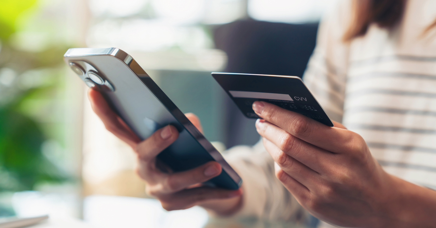 Automated payment reminders - A woman paying her medical bills online using a smartphone and credit card.
