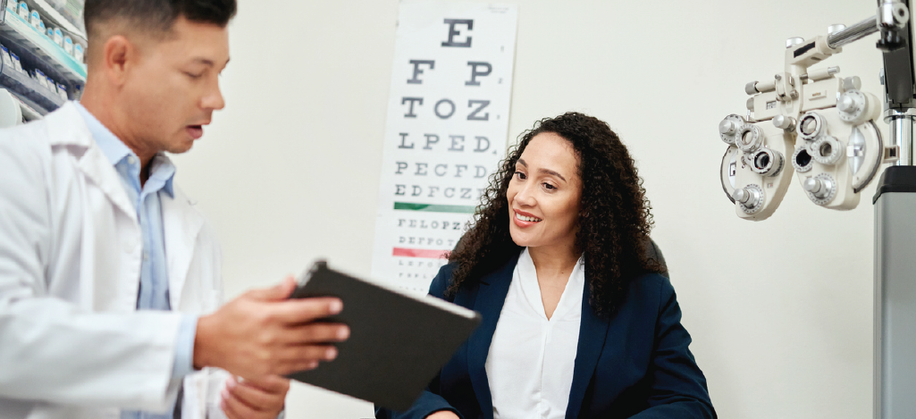 Flexible optometry billing options - A male optometrist holding a tablet device while discussing eye tests with his female patient.