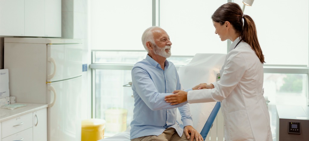 Smart billing solutions for better patient experience - A female doctor shaking hands with her senior male patient.