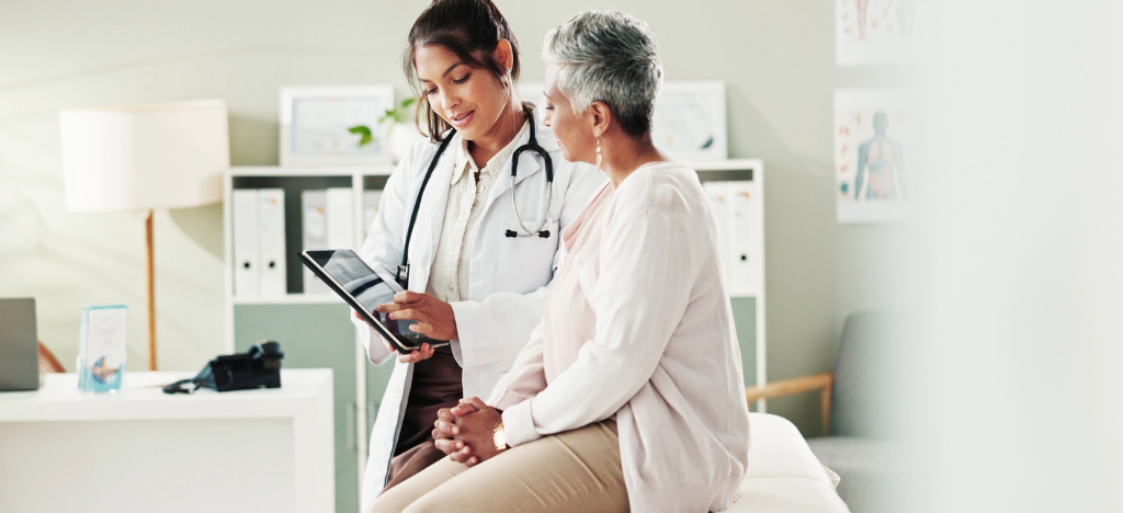Types of payment methods - A female doctor holding a tablet device while explaining different payment options to her senior female patient.