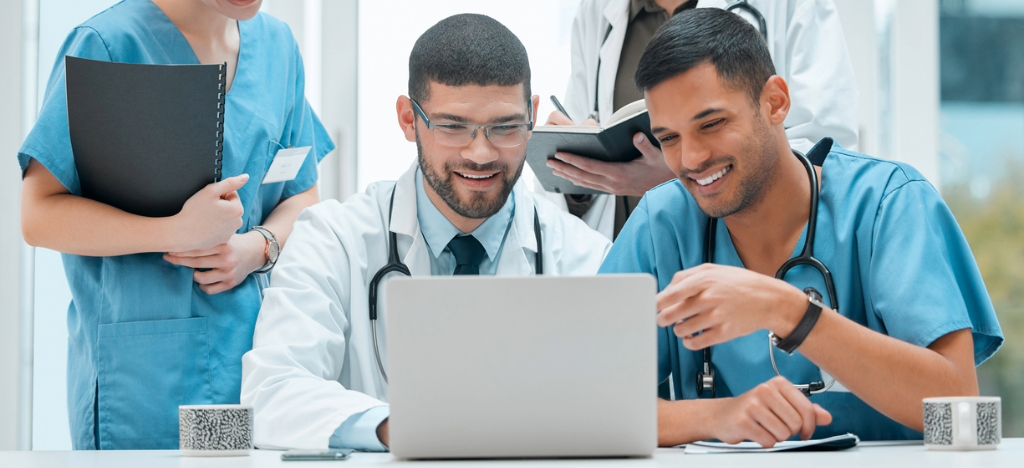 Patient billing support for healthcare providers - A team of medical professionals looking at a laptop while discussing their practice’s revenue performance.
