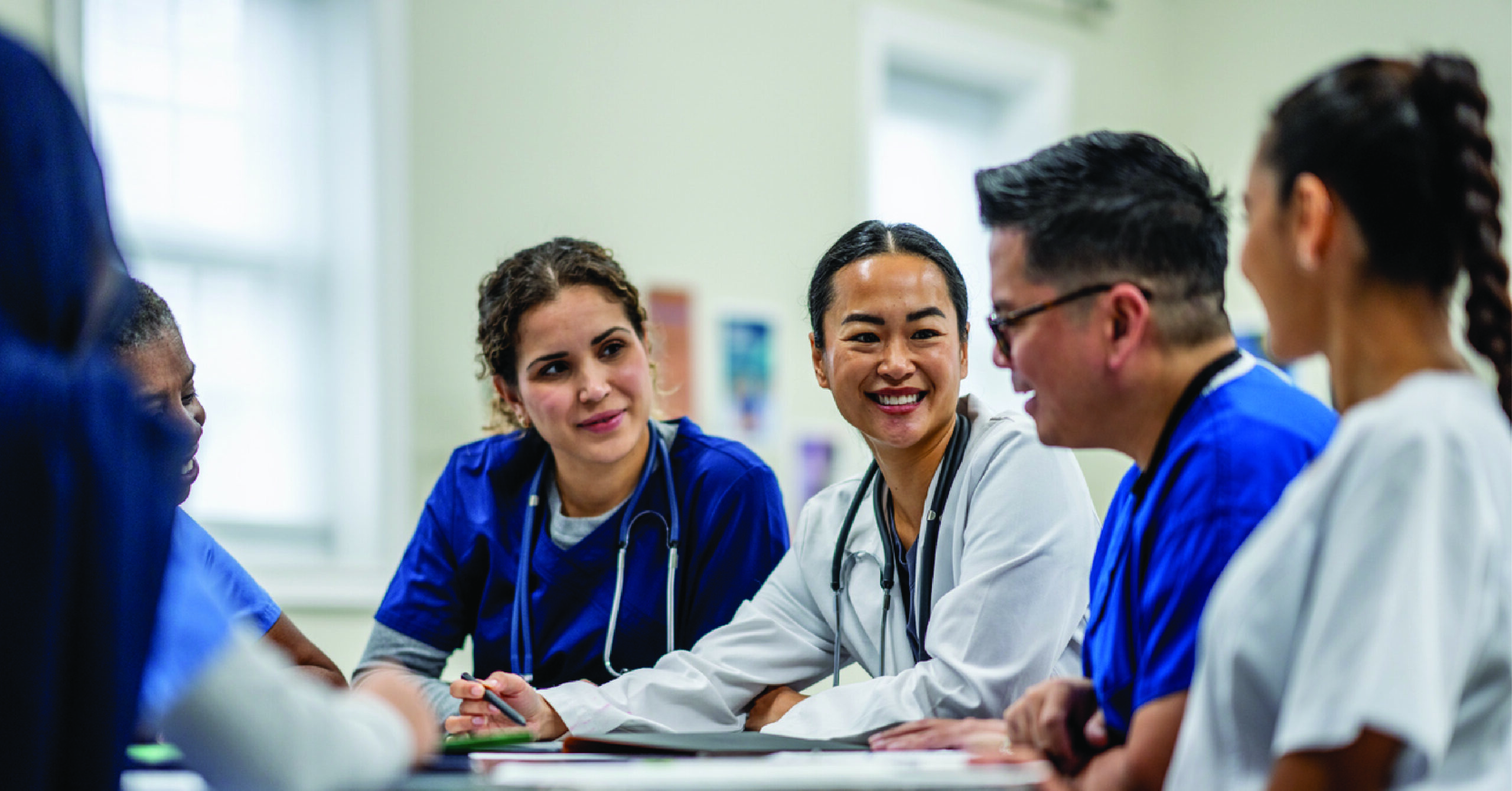 Preventing healthcare burnout - A female doctor having a meeting with her colleagues in an office.