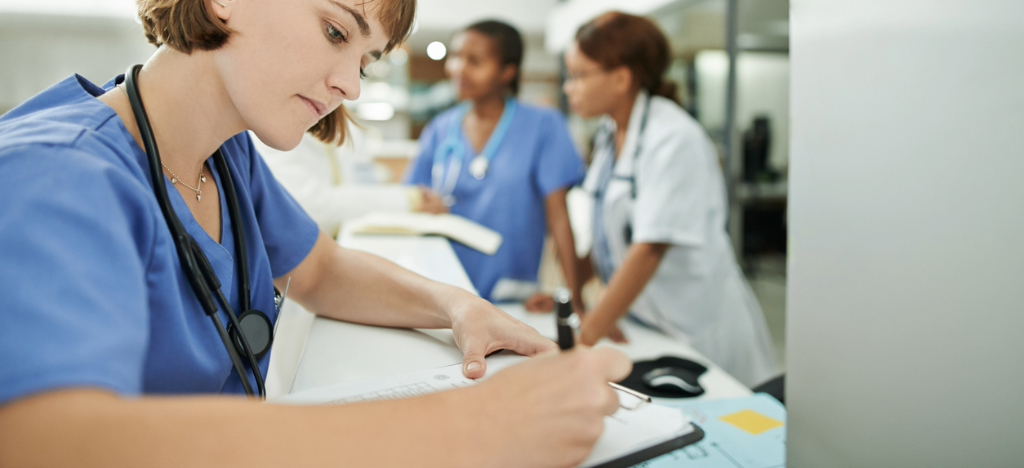 Modernizing your billing workflow process - A female hospital staff member filling out a patient’s billing information sheet.