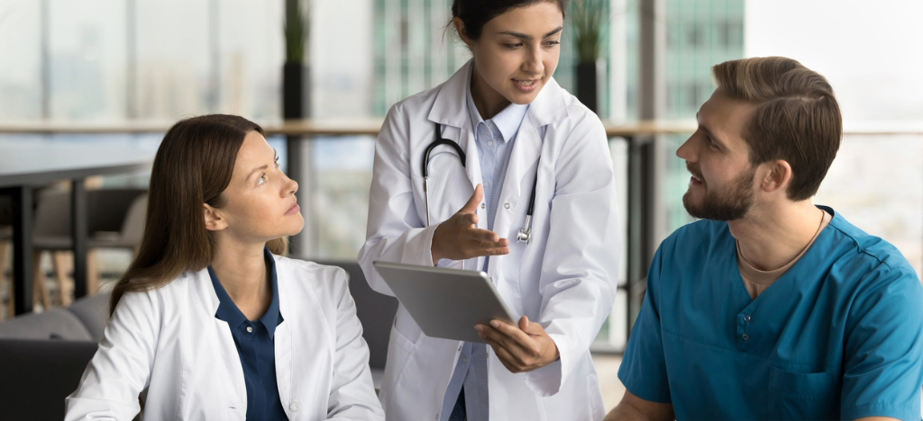 All-in-one communication - A female doctor holding a tablet device while explaining operational changes to her colleagues.