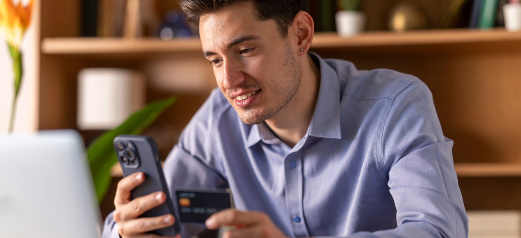 A man at home using his smartphone and credit card to settle his hospital bills.