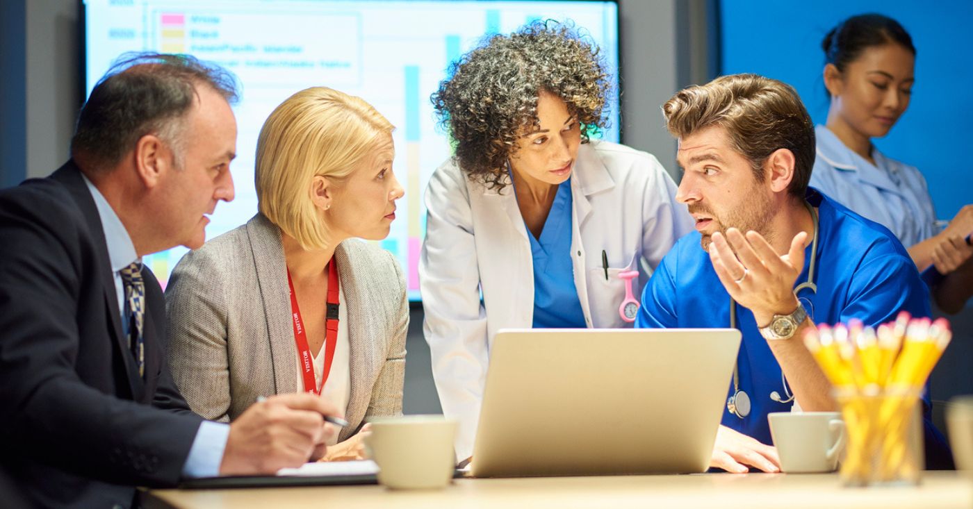Healthcare Revenue Cycle Management Companies: Diverse healthcare administration team discussing data on laptop.