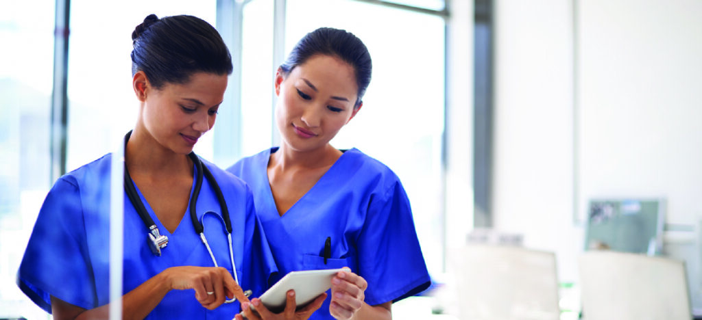 Using software for medical billing - Two female medical professionals reviewing patients’ medical bills using a tablet device.