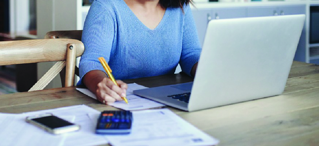 Encouraging patient financial responsibility - A woman at home reviewing and computing her bills.