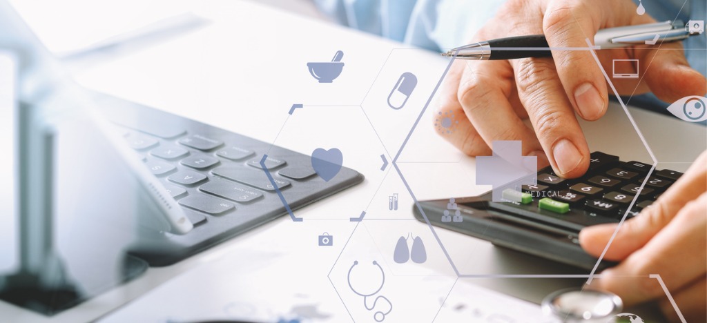 Enhancing patient financial experience - A male doctor computing his practice’s revenue using a calculator.