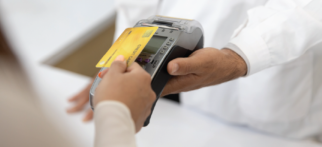 Safe medical credit card processing system - A female patient paying her medical bills using a credit card.