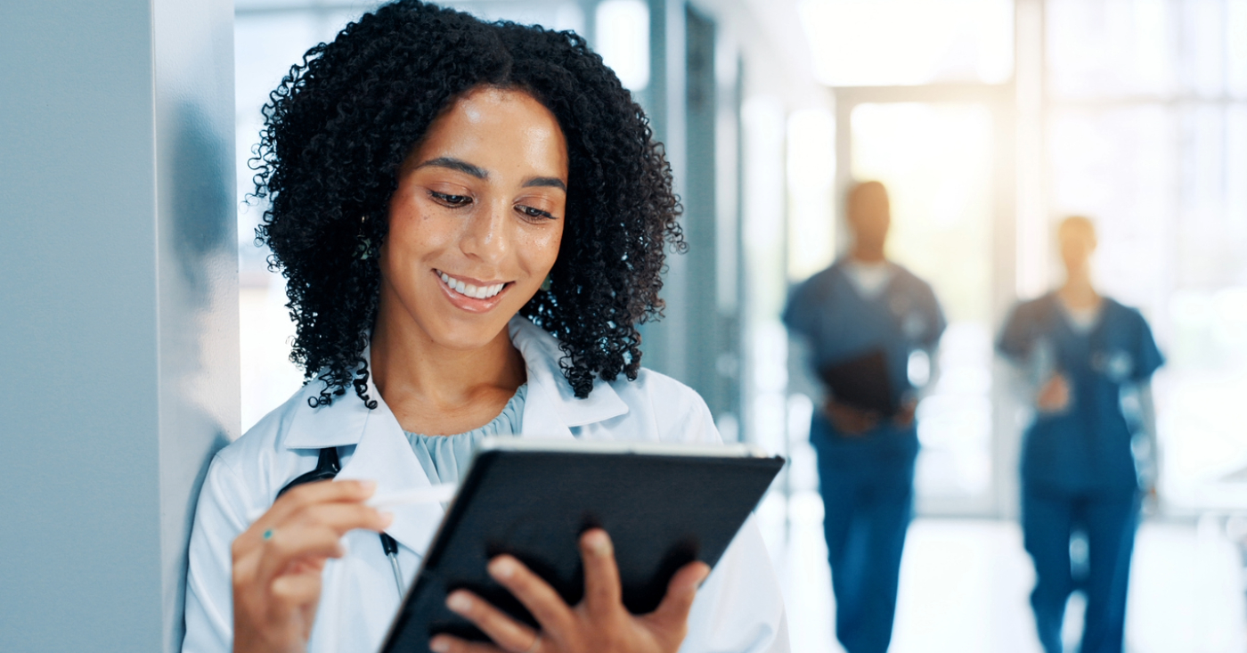 Billing checklist - A female doctor in a hospital using a tablet device to review patient collections.