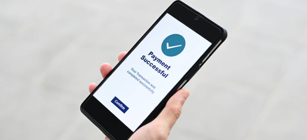 Payment Processing Ecosystem: Hand holding a smartphone showing a “payment successful” notification.