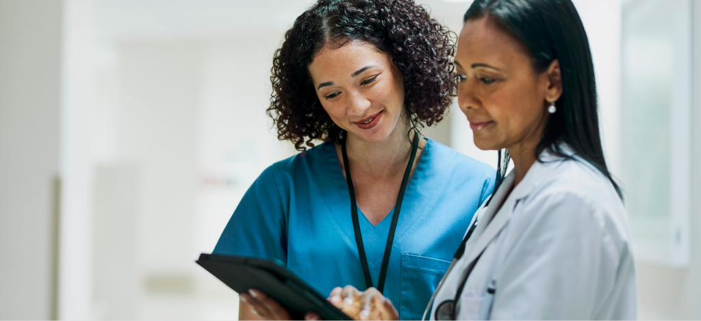 End-to-end RCM software - Two female medical professionals looking at their practice’s billing software through a tablet device.