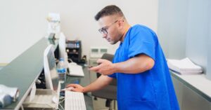 Healthcare staff using a mobile phone and the reception desktop pc.