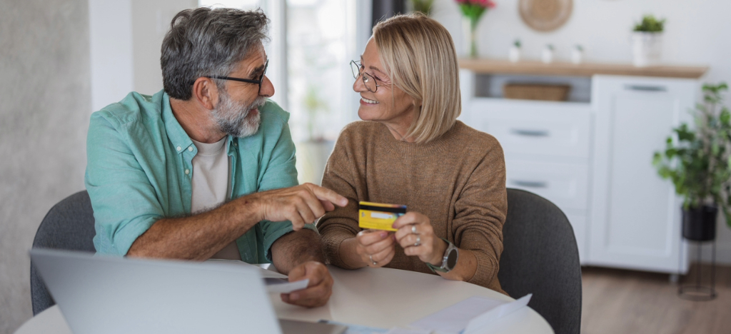 High-deductible health plans - A couple at home using a credit card while discussing how they will pay for their medical bills.