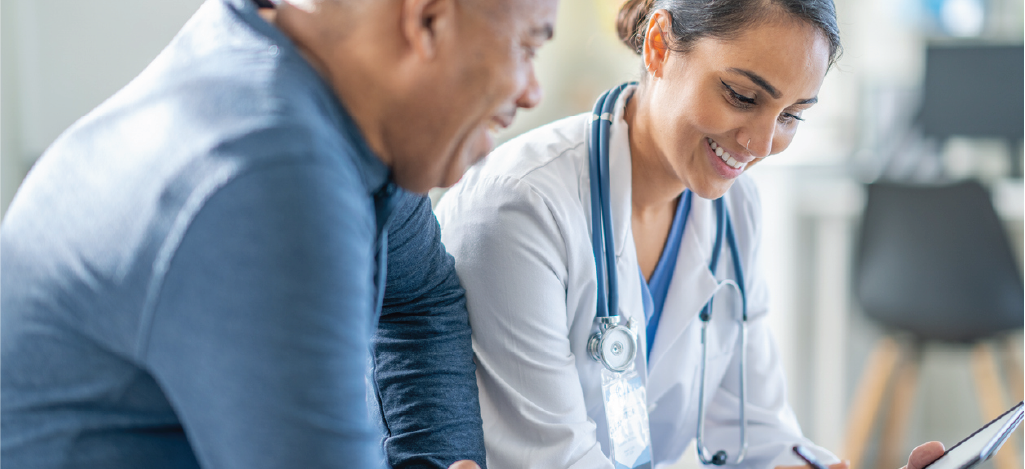 Offering medical billing solutions - A female doctor holding a tablet device while assisting a male patient with his medical bill.