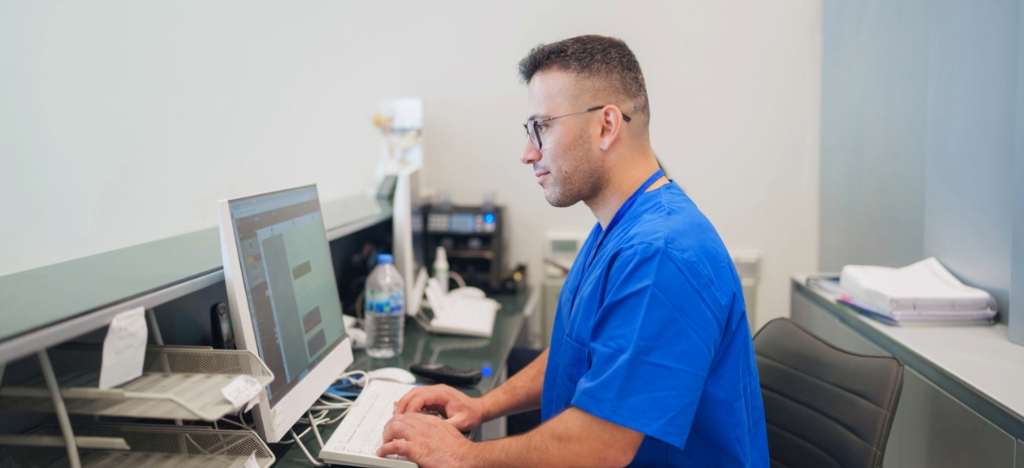 A male hospital staff member using a computer to check patient payments.