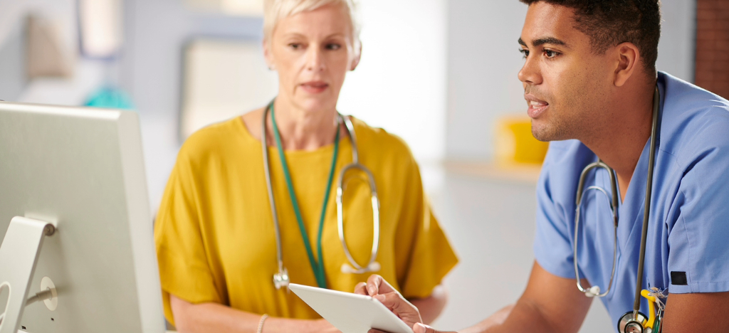 Electronic Bill Presentment and Payment - Two medical doctors using a tablet device and computer to review their patients’ bills.