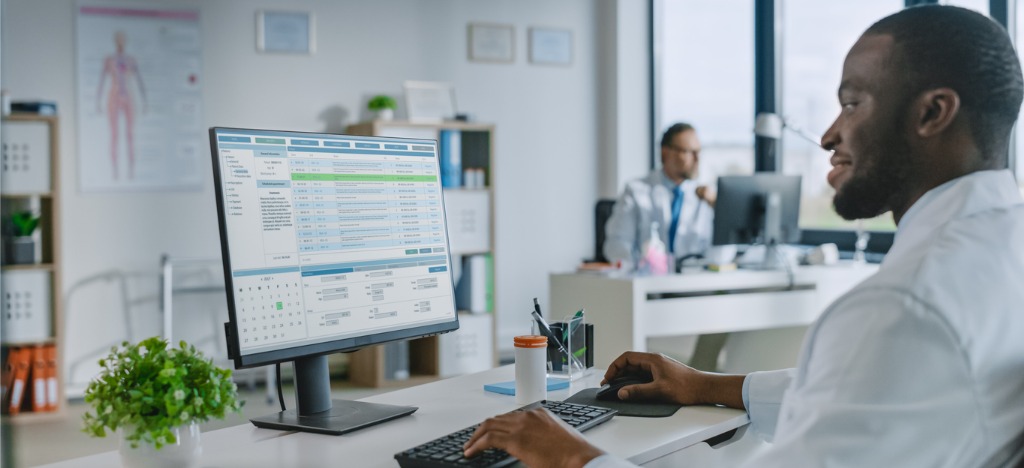 Billing process automation - A male doctor using a computer to check patient bills.