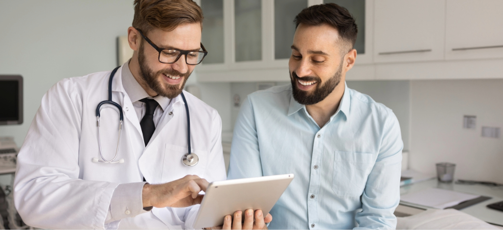A male doctor using a tablet device to explain a patient’s medical charges.