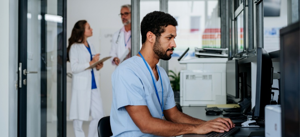 Strategies for reducing administrative burden - A male medical staff using a computer to accomplish his tasks.