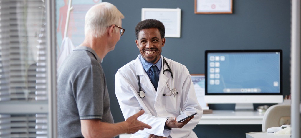 Improving medical billing technology - A male doctor talking to his senior male patient during a consultation.