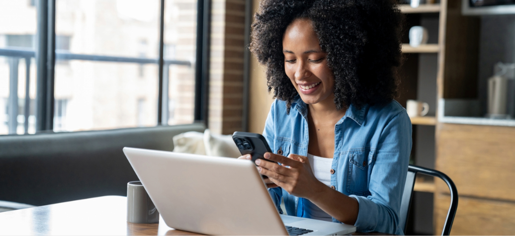 All-in-one communication - A woman at home using her smartphone and laptop to review her medical bills.