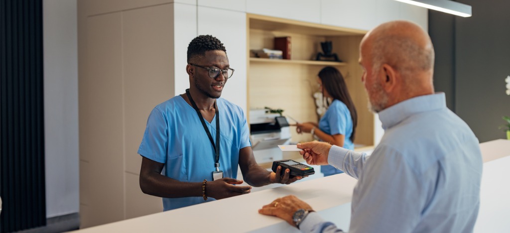 Automation in healthcare - A male hospital staff member helping a patient pay his medical bill.