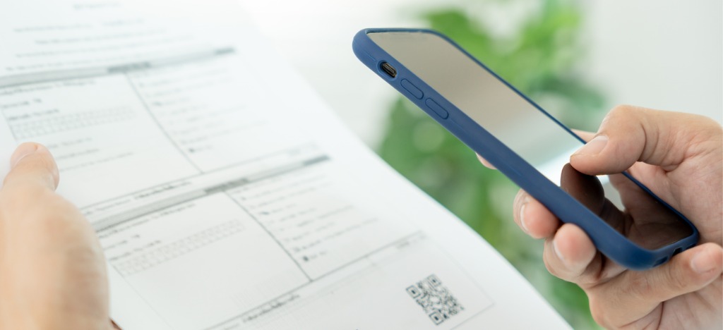 Mailed and eBills for payments - A man using a smartphone to scan a QR code on a printed bill.