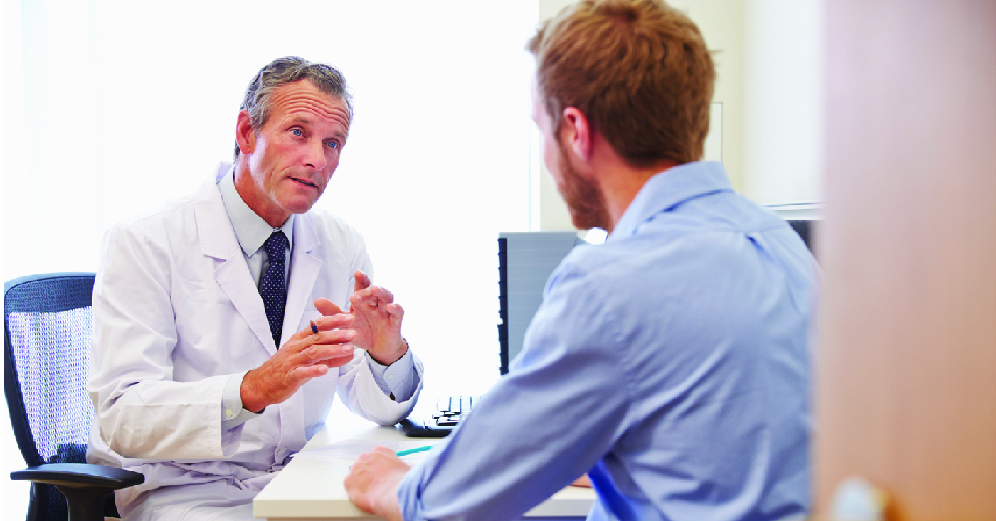 Improving patient financial responsibility - A male doctor speaking to a male patient during a medical consultation.