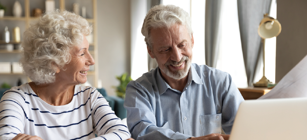 Senior couple paying medical bills at home using a laptop - compassionate patient collections concept.