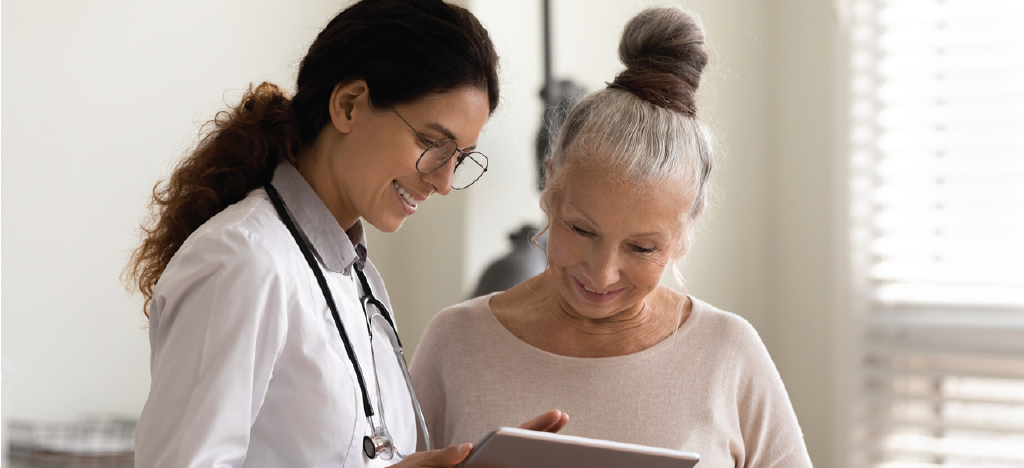 Compassionate patient collections - Female doctor using a tablet device to explain a senior woman’s medical bill.