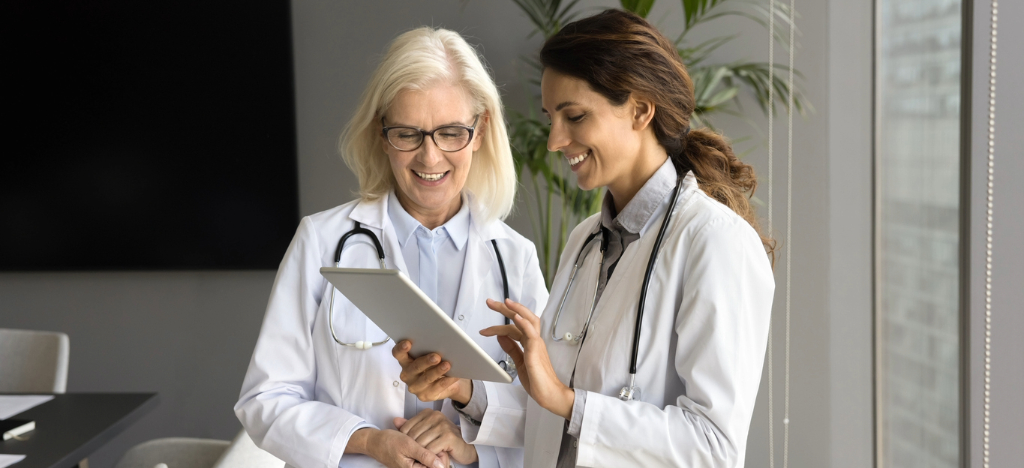 Get paid faster - Two female doctors using a tablet device to review their medical billing software.