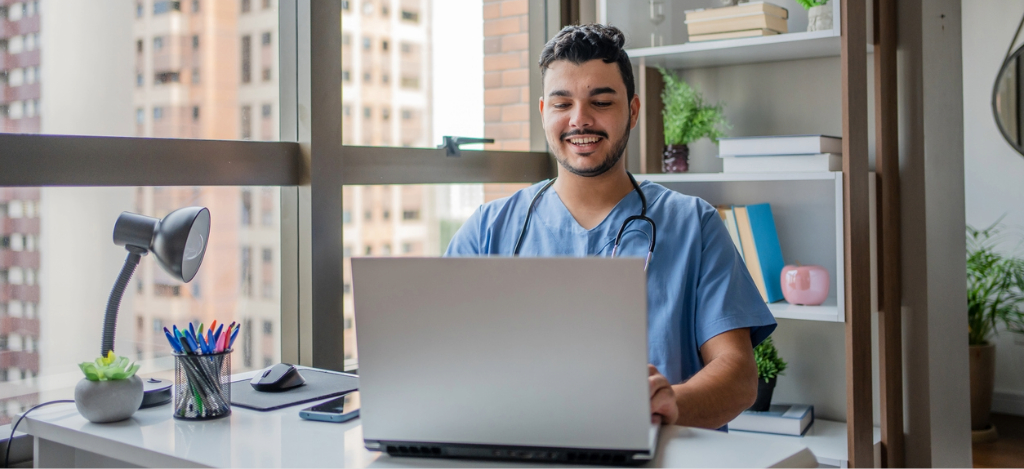 Patient messaging - A male doctor using a laptop to communicate with his patients virtually.