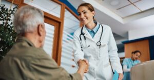 Mapping your payment journey - A female doctor shaking hands with her senior male patient.